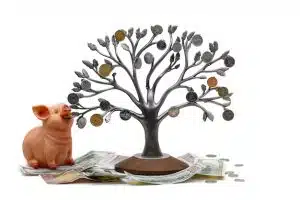 Piggy bank next to a metal tree with coins on its branches, symbolizing savings and financial growth.